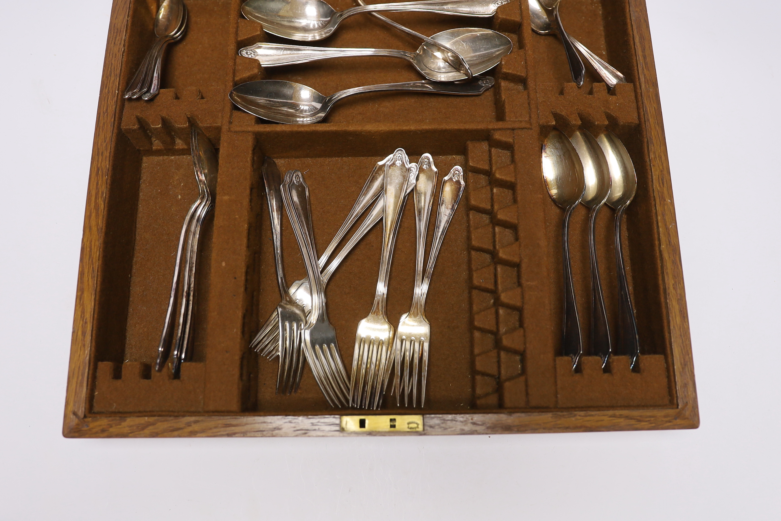 An oak cased canteen containing Sheffield ‘Super stainless’ flatware and a pair of plated candelabra, 46cm